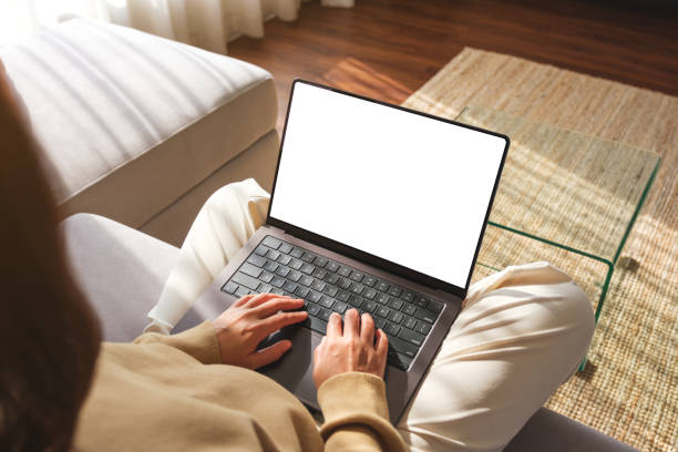 istock Mockup image of a woman working and typing on laptop computer with blank screen while sitting on sofa at home 2026810871
