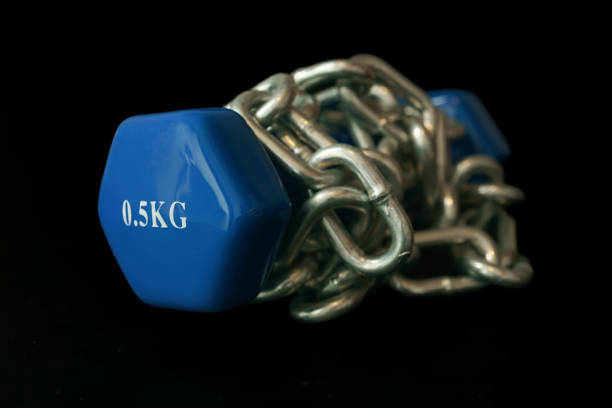 blue dumbbell tied with a chain isolated on a black background and copy space