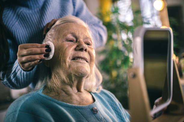 a young mother helps her old mother apply face cream