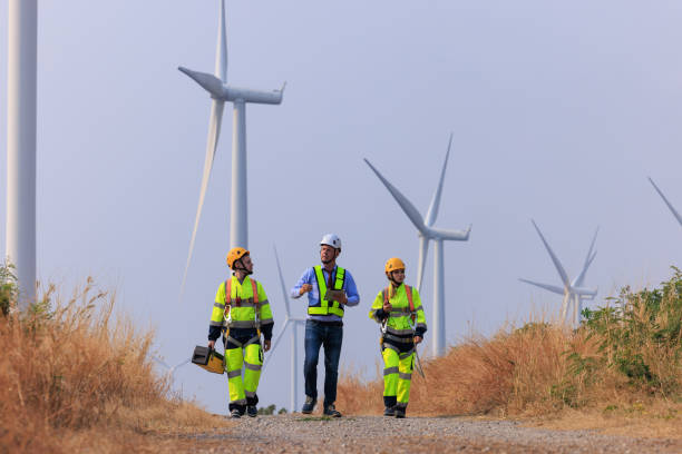 istock Engineers and inspector team wearing uniforms and helmets with equipment walking exploring and repairing electric wind turbines which are renewable energy for communities and agriculture. 2026885895