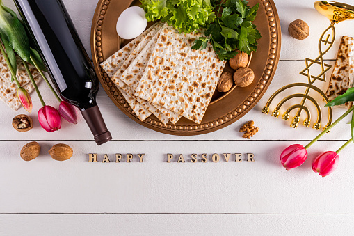 Festive background for the spring holiday of the Jewish Passover. Traditional foods, flowers, minor candlestick. Text of Happy Passover.