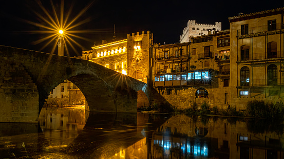 The passage of the river Matarraña through the medieval bridge of Valderrobres in the region of Matarraña in Teruel photographed at night with the river and its tower