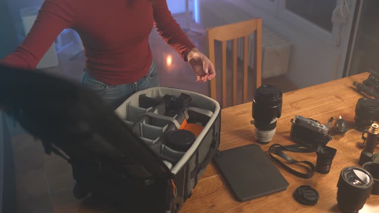 Young woman packing her photographic equipment in professional camera bag in studio