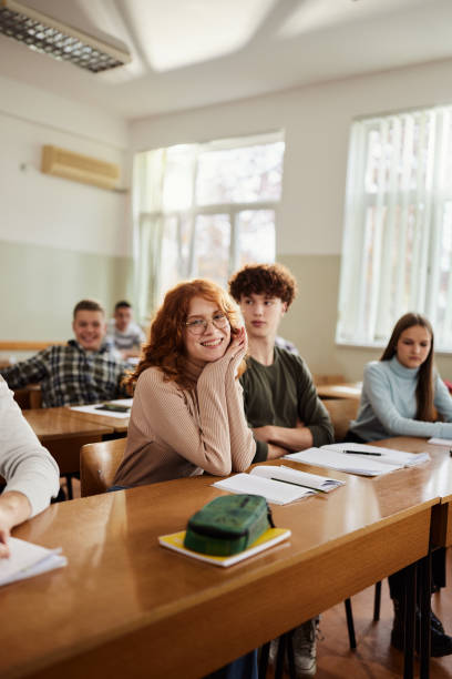istock Happy redhead student and her friends on a class at high school. 2027081972