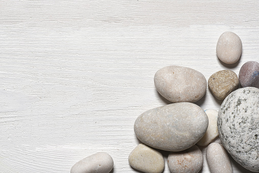 Sea pebble stones on the white wooden flat lay table background with copy space.
