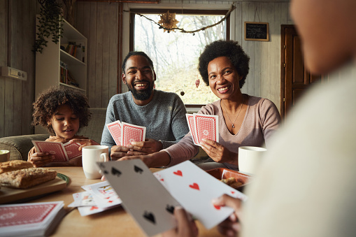 Happy black family enjoying while playing cards in the living room.