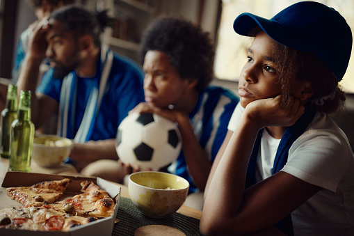 African American girl and her family feeling frustrated after their favorite soccer team has lost the match.