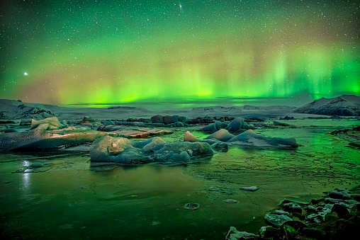 Glowing red and green Aurora Borealis over the icebergs at Jokulsarlon glacier, Iceland