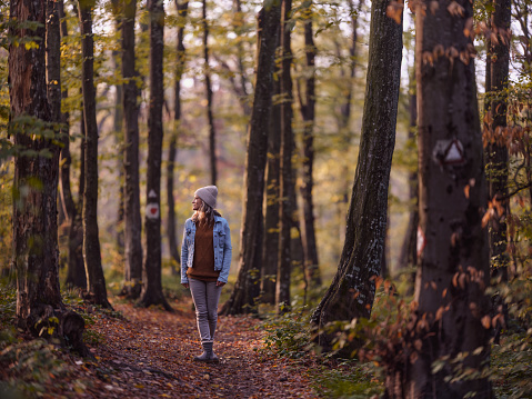 Young carefree woman day dreaming during autumn walk in the forest. Copy space. Photographed in medium format.