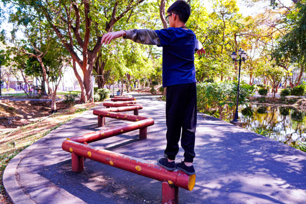 Picture of a boy practicing balancing on a zigzag log in a public exercise park.