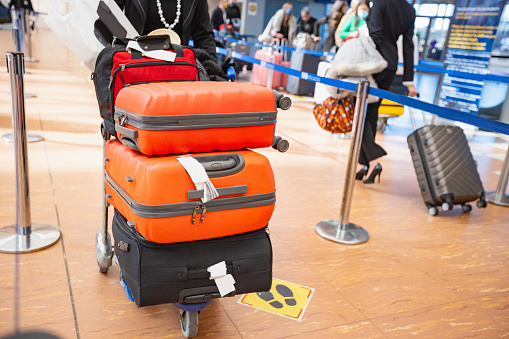 Pushing stack of suitcases on luggage cart at the airport arrival departure area