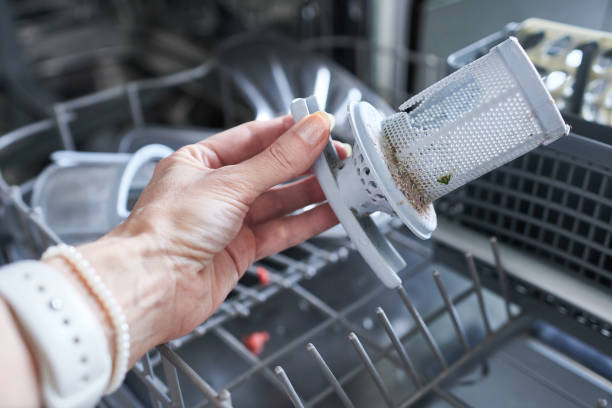 istock Broken dishwasher. Close-up of a woman's hand and a broken dishwasher filter. 2027134490