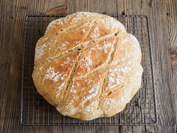 istock Sourdough bread with flour on a wire rack, rustic wood backdrop. 2027157319