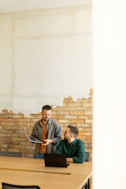 istock Collaboration in Motion, Professionals Working Together in a Modern Brick-Walled Office 2027163236