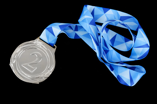 Silver medal with blue ribbon isolated on black background.