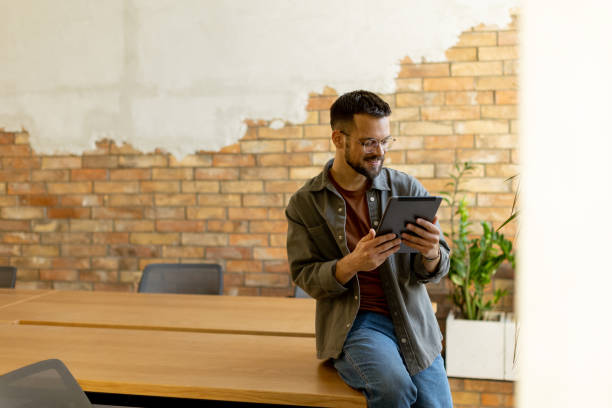 istock Smiling Man With Tablet in a Modern Brick-Walled Office 2027165862