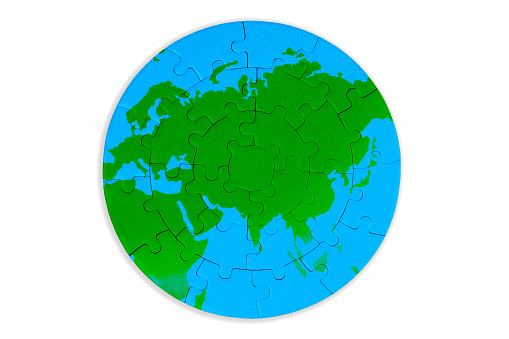 Circular puzzle map featuring rich green continents and serene blue oceans set against a white background. Unity, exploration, and environmental awareness related concept.