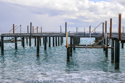 Wooden dock jutting out into the sea with a cloudy sky in the background