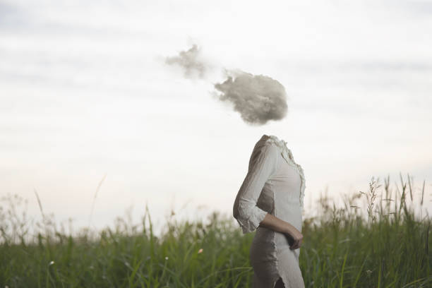 surreal woman with a cloud on her head walking freely and lightly in a meadow - imagination fantasy invisible women imagens e fotografias de stock