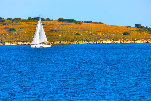 White yacht sailing near the island . Beautiful summer landscape. Luxury sailboat