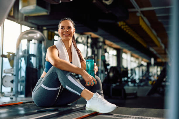 istock Young happy sportswoman having a water break while exercising in a gym. 2027276316