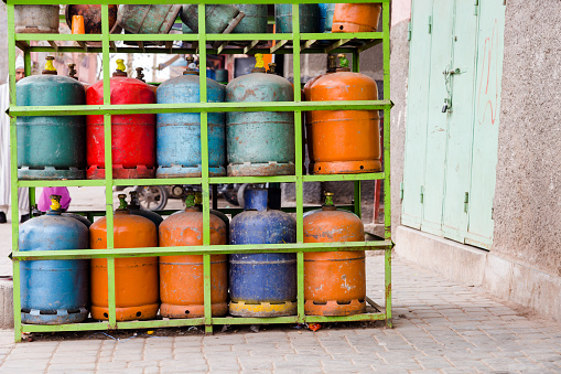 Colourful propane butane gas bottles stored on steel shelf. Natural gas bottles in gas station in Morocco.