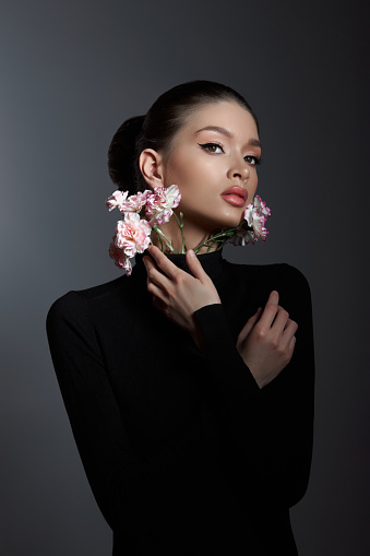 Woman in black with delicate pink flowers, embodying beauty and serenity. Captivating blend of nature and elegance