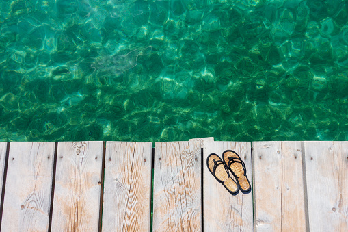 Flip flops on the wooden pier by the lake. Travel concept without people.