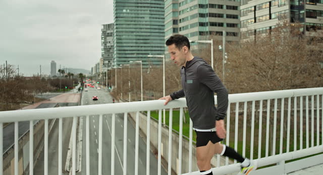 Athlete in late 40s warming up for run across footbridge