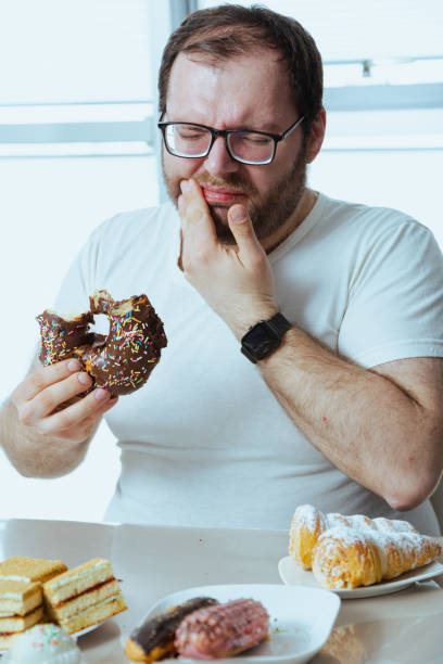 Man eats chocolate candies and feels toothache stock photo