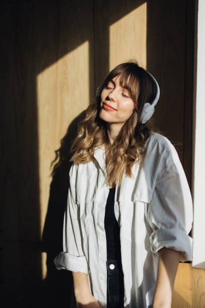 istock Morning Melodies: Beautiful Woman Enjoys Music in Sunlight 2027377113