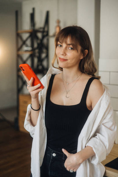 istock A cute, beautiful woman using a smartphone at home 2027378790