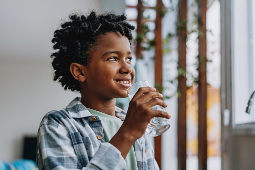 Portrait child boy drinking water at home