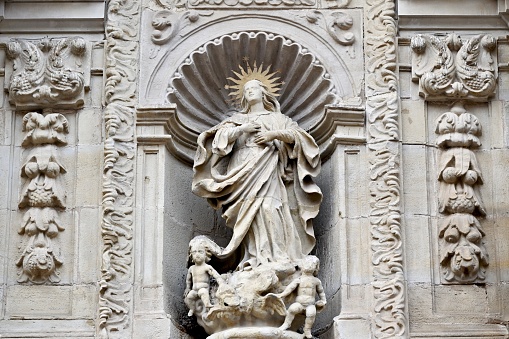 Votive capital with white statue of the virgin mary and baby jesus in her arms.