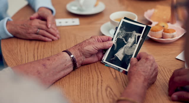 Hands, photograph and memory with senior friends thinking about the past while in a nursing home. History, vintage and retirement with an elderly group holding a picture closeup to remember life