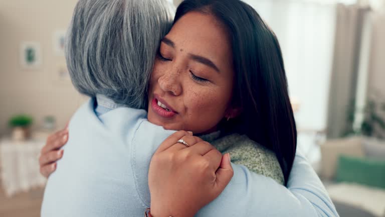 Love, retirement and a senior asian woman hugging her daughter in the living room of a home during a visit. Family, smile and an adult child embracing her happy mother together in an apartment