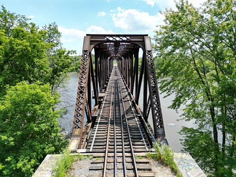 Laval, Canada – June 22, 2022: Rail bridge over river surrounded by trees