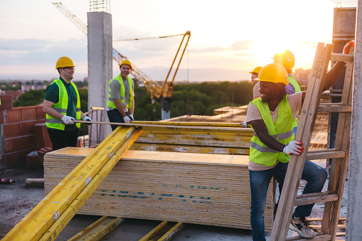 Male construction workers working on top of a roof.