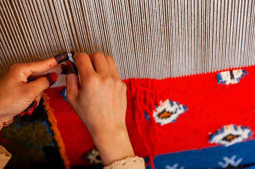 Berber woman weaving a carpet in a traditional house, Ouarzazate, Morocco. This old fashined form of weaving is very popular in the High Atlas mountains, specially in villages near Ouarzazate town.