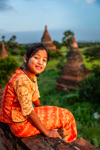 Young Burmese girl with thanaka face paint looking at an ancient temples of Bagan, Myanmar (Burma)