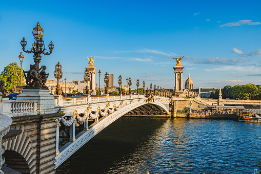 Arch bridge over the Seine River with golden ornament statues, Pont Alexandre III city road under the clear blue sky