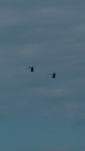 SUPER SLO MO Majestic Might: Low Angle View of Two Army Helicopters Against Cloudy Sky