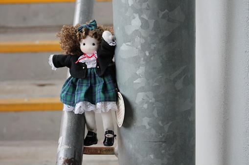 Cute Adorable Doll Sitting on the Stair Railing in Front of Yellow Stairs, Cute Childhood