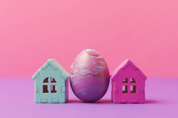 istock Decorative easter egg painted in fluid art technique and houses against pink background with copy space 2027497660