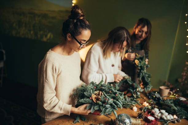 istock Happy women making Christmas wreath using natural pine branches and festive decorations. 2027503237