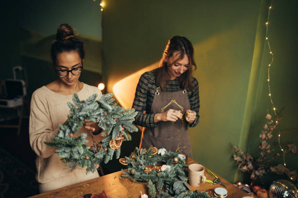 istock Happy women making Christmas wreath using natural pine branches and festive decorations. 2027503240