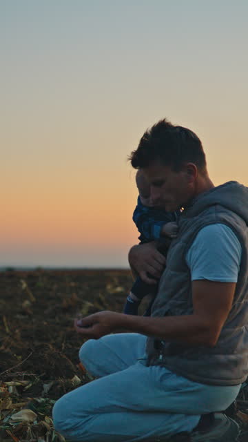 SLO MO Male Agronomist Carrying Son and Analyzing Soil in Field against Sky During Sunset