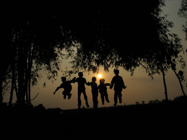Natural silhouettes of children chatting and playing under a bamboo tree