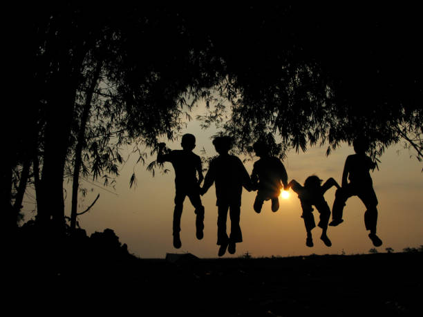 Natural silhouettes of children chatting and playing under a bamboo tree