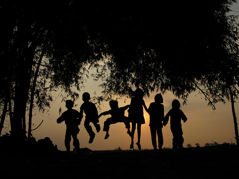 Natural silhouettes of children chatting and playing under a bamboo tree